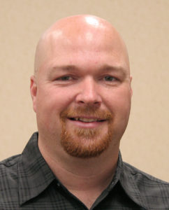 Headshot of a smiling man with bald head and goatee.